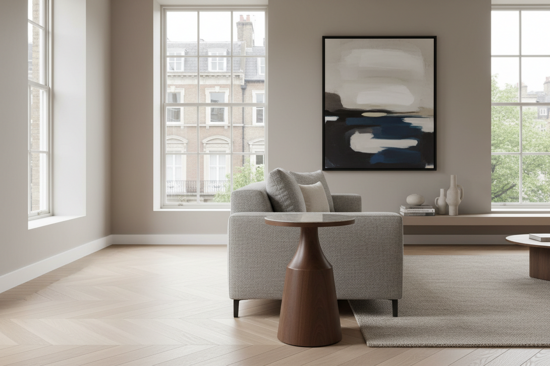 Modern living room with grey sofa, round brown side table, and abstract painting.